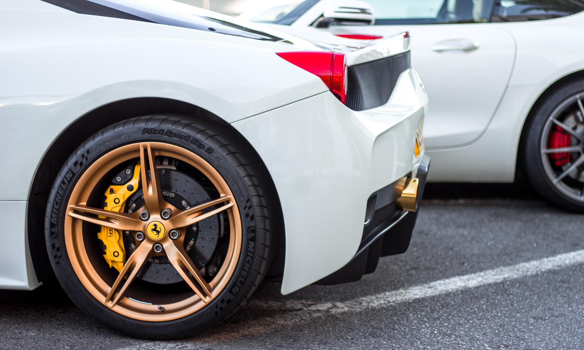 This shows the side profile of a white car with the golden wheels being the highlight of the composition.